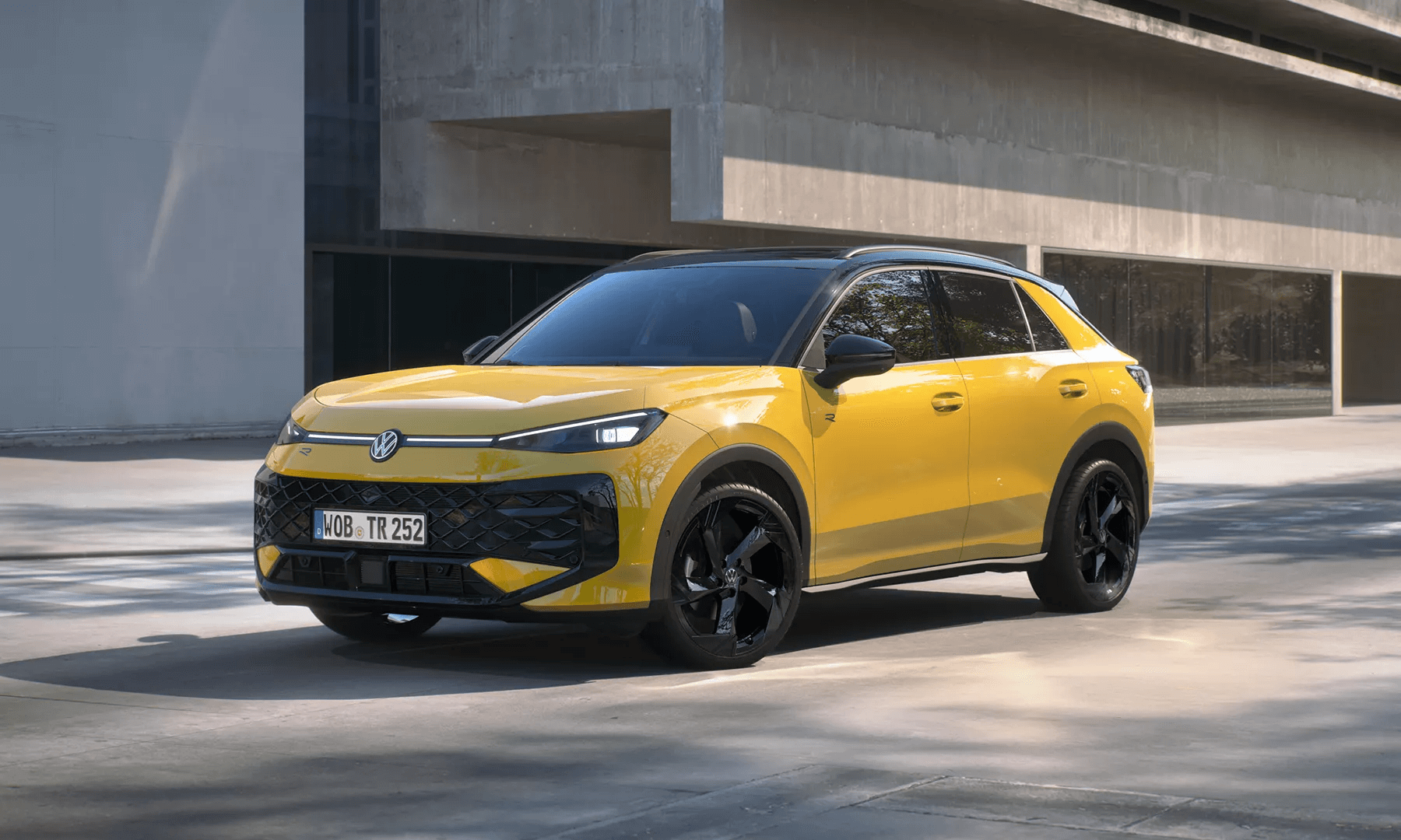 Kollane Volkswagen T-Roc R-Line seisab hoone ees mustade velgedega.