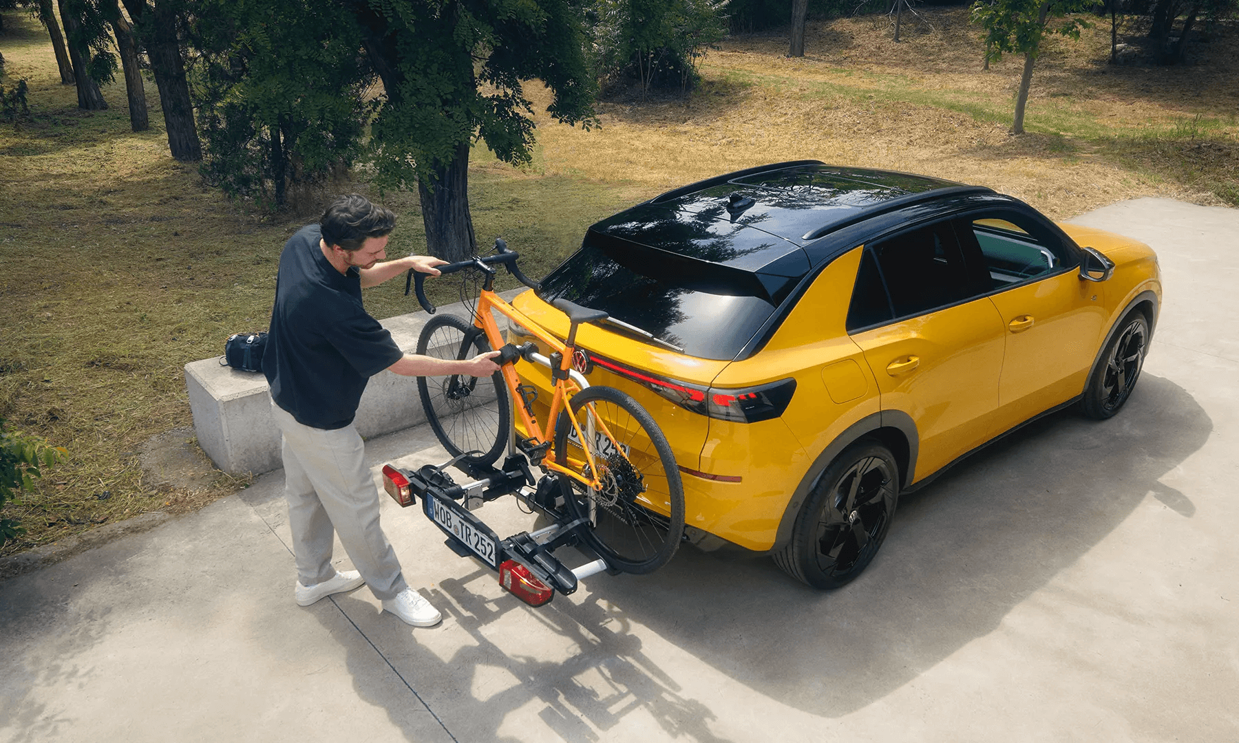 Mees kinnitab oranži jalgratast Volkswagen T-Roc haagise külge.